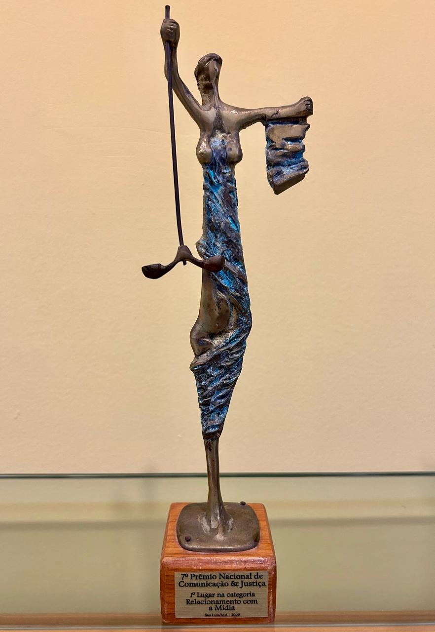 Estátua na cor preta apoiada em base de madeira na cor marrom