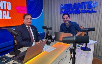 Foto mostra dois homens em um estúdio de rádio. Ambos estão sentados.
