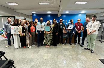 Foto mostra um grupo de pessoas, em pé, dentro do auditório da EJud-16. 