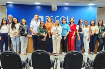 Foto mostra várias pessoas em pé uma ao lado da outra. Todas estão em um auditório