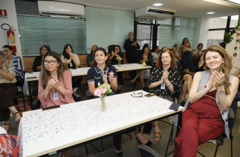 Foto mostra mulheres sentadas e aplaudindo.