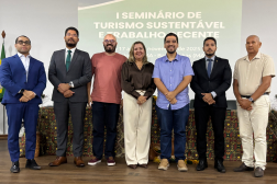 Foto de uma mulher loira ladeada por seis homens, todos de pé.