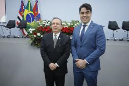 Foto mostra dois homens em pé. Ambos usam terno. 