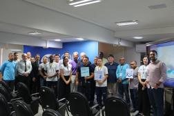 Foto de pessoas em pé, dentro de um auditório.