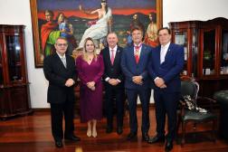 Foto mostra uma mulher e quatro homens. Todos estão em pé, um ao lado do outro.