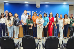 Foto mostra várias pessoas em pé uma ao lado da outra. Todas estão em um auditório