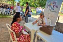 Foto mostra duas mulheres sentadas à mesa. Ao fundo um banner com a informação: Pop Rua Jud Maranhão