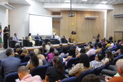 Foto de auditório com plateia e autoridades no palco.