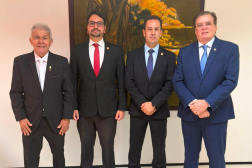 Foto mostra 4 homens usando terno escuro. Ambos estão em pé, um ao lado do outro