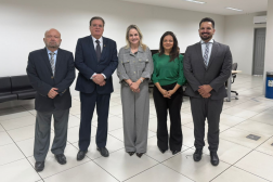 Foto mostra cinco pessoas em pé. Todos usam roupas sociais
