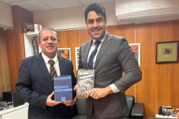 Foto mostra dois homens em pe, um ao lado do outro. Ambos usam terno.