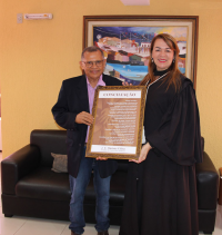Presidenta Solange e o poeta J.C. Ramos posam com o quadro da poesia "Conciliação"