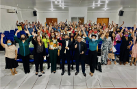 Várias pessoas juntas em um auditório acenando em comemoração ao lançamento do Programa Infância sem Trabalho em Pinheiro