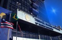 Foto da fachada principal do prédio-sede do TRT-16 iluminada na cor azul. À esquerda, estão hasteadas as bandeiras do Brasil, Maranhão e do TRT-16 .