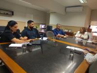 Foto mostra a Diretora-Geral do TRT-16 Fernanda Cristina Marques sentada à mesa de reunião com outras três pessoas. 