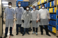 Foto mostra pessoas em pé, posicionadas em frente a prateleiras com caixas de processos.