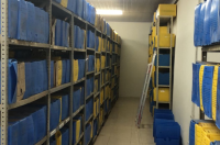 Foto mostra prateleiras com caixas de arquivos.