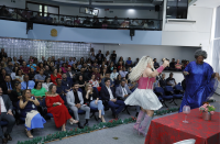 Foto mostra a presidente do TRT-16, desa. Márcia Andrea Farias e servidores, terceirizados e estagiários sentados assistindo a peça de teatro Pão com Ovo.