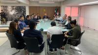 Foto de mesa de reunião com várias pessoas em volta. 