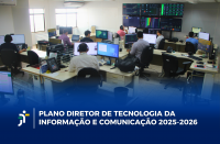 Foto mostra várias pessoas sentadas no ambiente de trabalho. Cada mesa, tem um computador sobre ela. Ao fundo, funciona uma painel com várias luzes coloridas. Na parte da baixo a informação: PLANO DIRETOR DE TECNOLOGIA DA INFORMAÇÃO E COMUNICAÇÃO 2025-2026
