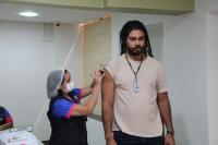 Foto mostra duas pessoas. Uma mulher aplicando uma vacina no braço direito de um homem durante a campanha da Semana de Saúde do TRT16 (Maranhão)