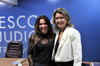 Foto mostra duas mulheres em pé no auditório da Escola Judicial