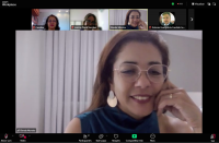 Foto de tela de computador mostrando videoconferência, com mulher clara de cabelos escuros (a palestrante) em destaque, ao centro. No topo, fotos de três mulheres e um homem como participantes.