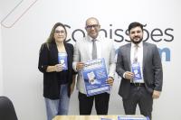 Foto mostra o secretário-geral da Presidência, George Adriano de Oliveira Costa, acompanhado da assessora administrativa da Diretoria-Geral, Lêda Raquel Araújo ao lado do presidente da Comissão de Direito Trabalhista da OAB/MA, Luiz Carlos Frazão. Eles estão em pé segurando o cartaz e o folder do programa Quita Facil