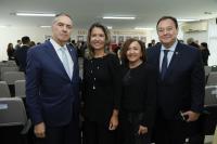 Foto mostra duas mulheres ao centro e dois homens nas extremidades. Eles estão em pé, diante de cadeiras de um auditório