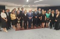 Foto mostra um grupo de pessoas, entre homens e mulheres dentro de um auditório. Todos estão em pé, um ao lado do outro, posicionados para uma foto.