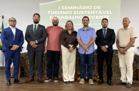 Foto de uma mulher loira ladeada por seis homens, todos de pé.