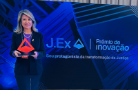 Foto mostra uma mulher segurando um troféu de acrílico. Ao lado a informação. J.Ex. Prêmio de Inovação