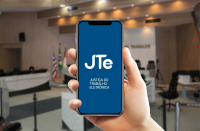 Arte feita com uma imagem de uma mão segurando um celular. Na tela, a informação: JTe Justiça do Trabalho Eletrônica