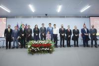 Foto mostra pessoas em pé em uma auditoório.