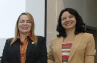 Foto mostra duas mulheres, em pé. Uma ao lado da outro