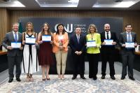 Foto mostra várias pessoas em pé, uma ao lado da outra. 