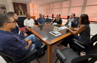 Foto mostra um grupo de pessoas sentados à mesa, 