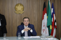 Foto mostra um homem sentado usando um terno azil