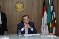 Foto mostra um homem branco usando um terno azul. Ao lado direito bandeiras do Brasil, Maranhão e da Justiça do Trabalho
