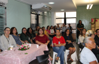 Foto mostra mulheres sentadas acompanhando uma palestra.