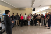 Foto mostra um homem usando um terno, ele está em é falando com estudantes de direito