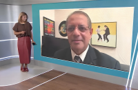 Foto mostra um homem de terno sendo entrevistado por uma mulher. 