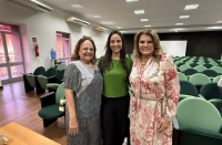 Foto mostra três mulheres, em pé uma ao lado da outra.