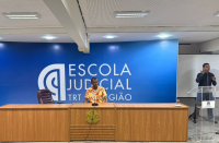Foto mostra um homem, sentado realizando uma palestra.