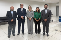 Foto mostra cinco pessoas em pé. Todos usam roupas sociais