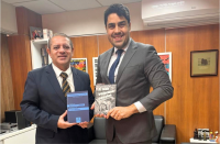 Foto mostra dois homens em pe, um ao lado do outro. Ambos usam terno.