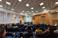 Foto mostra um auditório com pessoas sentadas.