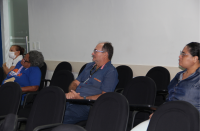 Foto mostra pessoas sentadas em cadeiras dentro de um auditório