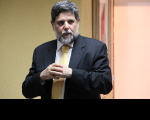 Ministro Caputo Bastos vestido com terno escuro e gravata amarela.