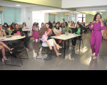 Foto de várias mulheres sentadas e de uma palestrante (que está em pé) em evento do Outubro Rosa